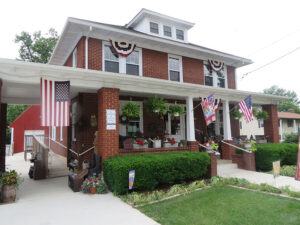 Brick building with American flags and decor items on the porch